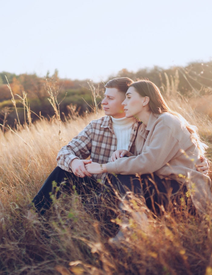 Harmony in Nature: A Symbol of Zodiac Signs & Compatibility Couple sitting in a meadow holding hands, embodying zodiac signs & compatibility